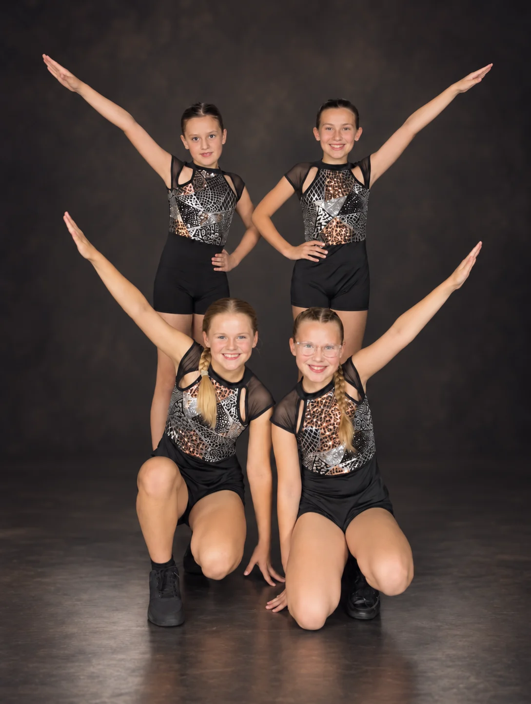 Four ESSOPA children in black and silver costumes posing together after a performance